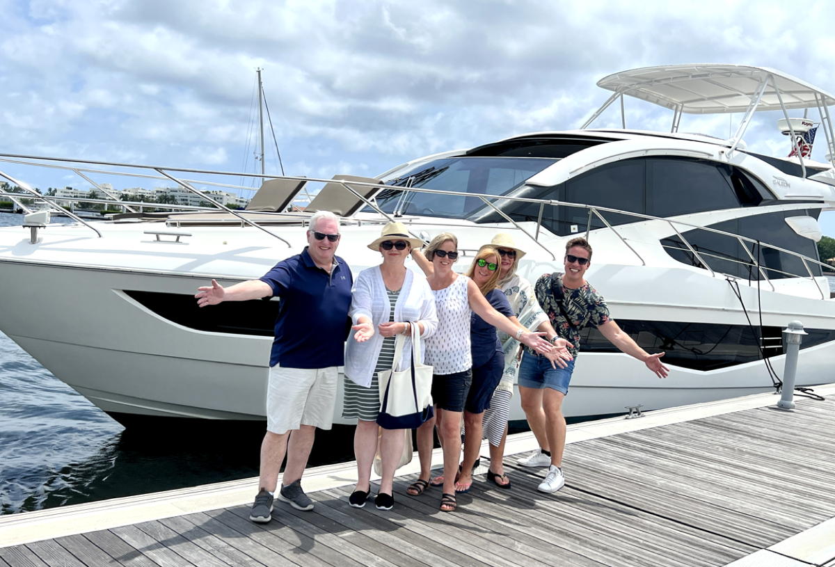 From left: Paul Larcher, Naomi Rogers, Carolyn Kremer, Catherine Davis, Leanne Toushan and Michael Pihach pose in front of a yacht, courtesy of Lots of Yachts/Lots of Spots, in West Palm Beach. (Supplied)